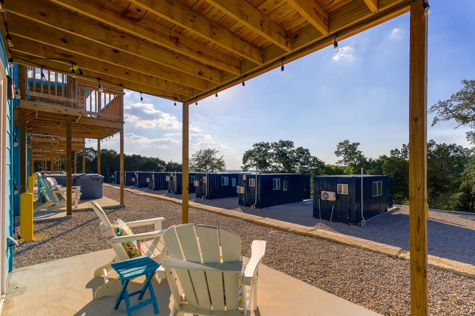 Covered cedar pergola patio with Adirondack chairs overlooking container homes at The Container Retreat