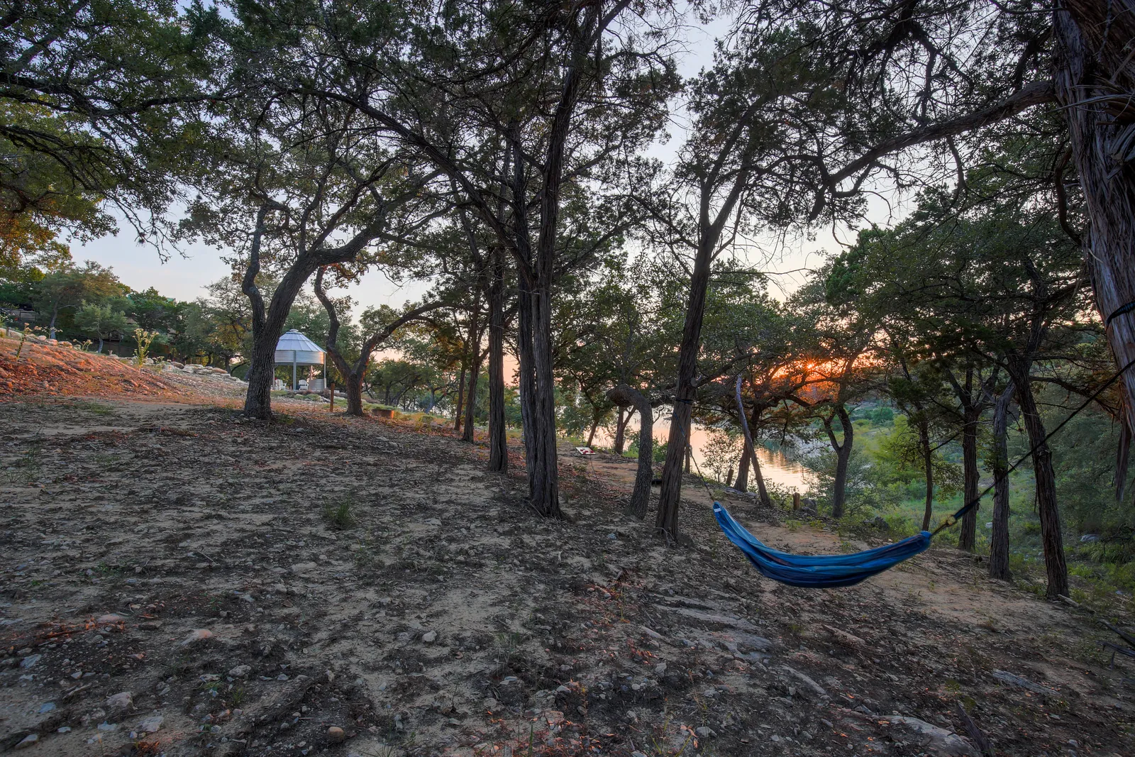 Lakeside wooded grounds with a hammock at sunset at The Container Retreat near Canyon Lake